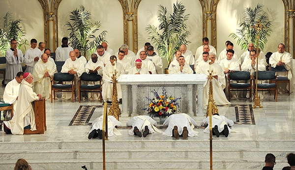 Bishop Richard J. Malone prays as the candidates, Father Gerard Skrzynski, Father Peter Santandreu, Father Paul Stanislaw Cygan and Father Peter Nsa Bassey, lie prostrate before the altar during the Ordination Mass at St. Joseph Cathedral. (Dan Cappellazzo/Staff Photographer)